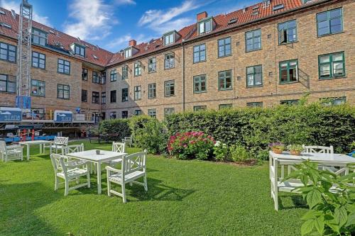 Comfortable stay in Copenhagen, single room في كوبنهاغن: مجموعة من الطاولات والكراسي البيضاء أمام المبنى