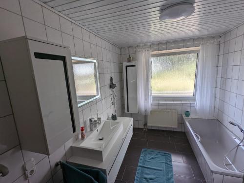 uma casa de banho com um lavatório, uma banheira e um espelho. em Panoramalounge em Porta Westfalica