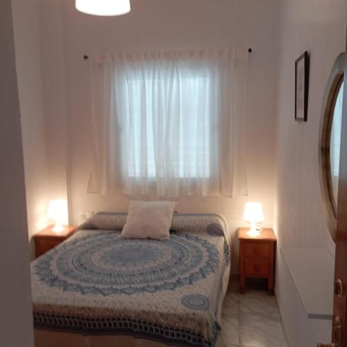 埃爾博斯克的住宿－Ático Los Arcos，一间卧室配有一张带两盏灯的床和一扇窗户。