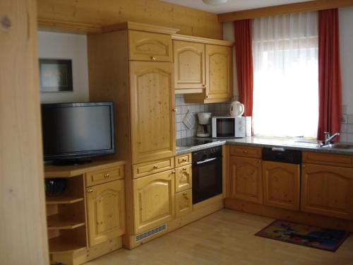 a kitchen with wooden cabinets and a tv in it at Chasa Valetta in Samnaun