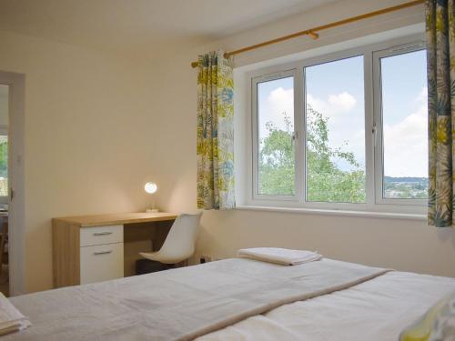 1 dormitorio con 1 cama, escritorio y 2 ventanas en View Point, en Stokeinteignhead