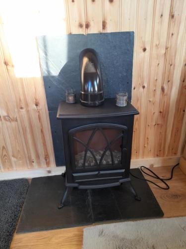 a wood stove with a tea kettle on top of it at Sunset View Shepherds Hut in Dalmally