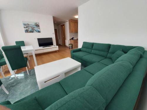 a living room with a green couch and a table at Sara Sarajevo in Bjelašnica