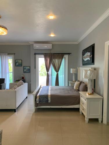 a bedroom with a bed and a couch and a window at Villa Segovia in Cozumel