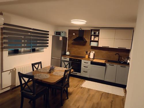 a kitchen with a table and chairs and a kitchen with a refrigerator at Kod Dida in Gospić