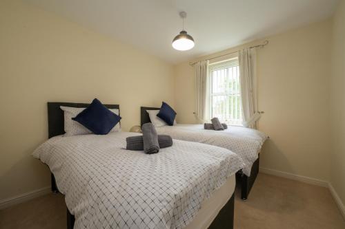 two twin beds in a room with a window at Luxury 2-bedroom 2-bathroom city centre apartment in Lichfield