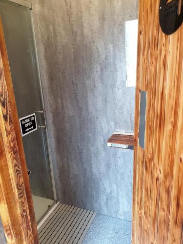 a bathroom with a shower with a sign on the wall at The Hobbit House and Secret Garden in Taunton