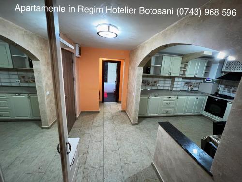 a large kitchen with white cabinets and an orange wall at Apartament Ultra Modern 2 camere mari +1 camera mai mica in Botoşani