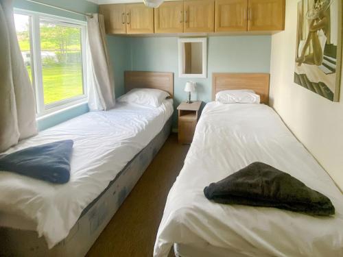 2 Einzelbetten in einem Zimmer mit Fenster in der Unterkunft Wye Lodge in Aberedw