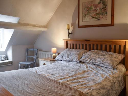 a bedroom with a bed and a chair and a window at Cosy Cottage in Bourton on the Hill