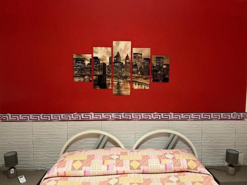 un dormitorio con una pared roja con una pintura de una ciudad en La loggia di Ale, en Palermo