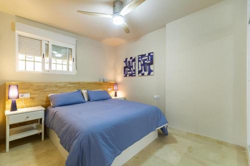 ein Schlafzimmer mit einem blauen Bett und einem Fenster in der Unterkunft Vistas Azules -- remodeled, large terrace, spectacular ocean views and beach level access in Torremolinos