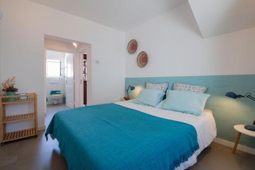 a bedroom with a large bed with a blue blanket at Casa no Rio - River House in Vila Nova de Milfontes