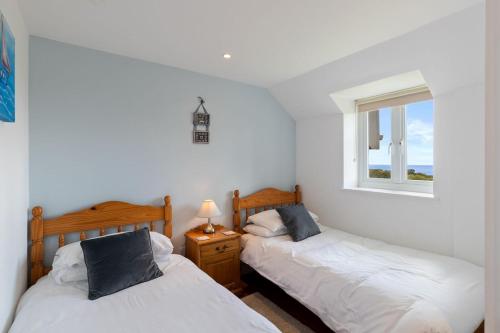two beds in a room with two windows at Stable Cottage - QC1789 in Llandyssiliogogo