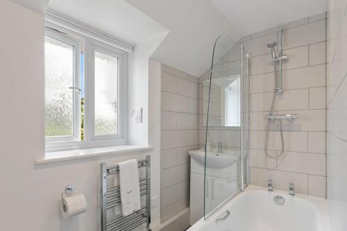 a white bathroom with a tub and a glass shower at Stable Cottage - QC1789 in Llandyssiliogogo
