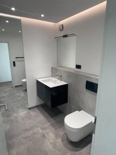 a white bathroom with a toilet and a sink at Luxus Apartment mit Skyline View. in Frankfurt