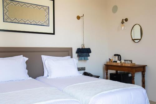two beds in a bedroom with a table and a mirror at House 1923 Boutique Hotel in Pano Lefkara