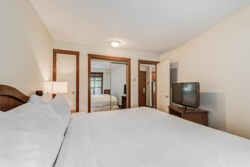 a bedroom with a white bed and a television at Blackcomb Springs Suites by CLIQUE in Whistler