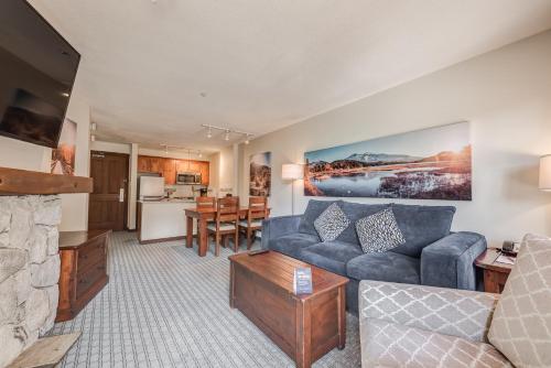 a living room with a blue couch and a kitchen at Blackcomb Springs Suites by CLIQUE in Whistler