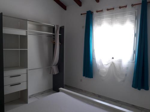 a bedroom with a window with a blue curtain at Villa les Alizés in Morne Blanc