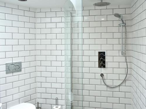 a white tiled bathroom with a shower and a toilet at Lake View Farm in Watermillock