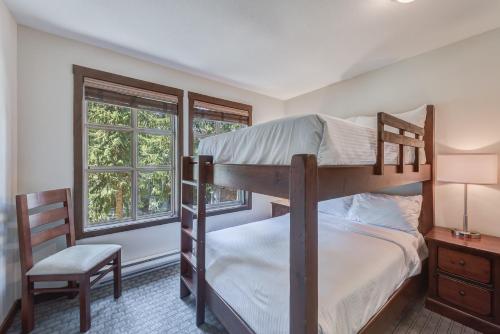 a bedroom with two bunk beds and a chair at Blackcomb Springs Suites by CLIQUE in Whistler