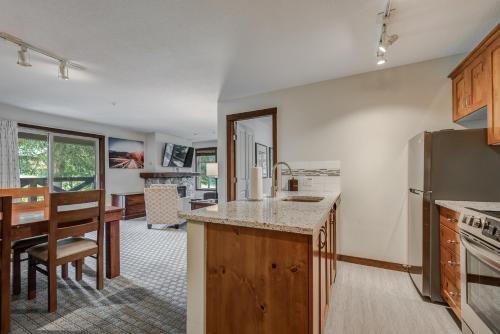 a kitchen with a refrigerator and a dining room at Blackcomb Springs Suites by CLIQUE in Whistler