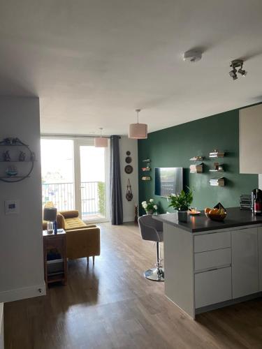 a kitchen and living room with green walls and a table at Lovely and comfortable flat in Chelsea. in London