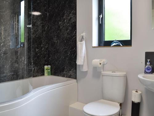 a bathroom with a toilet and a tub and a sink at Juniper Barn in Westward