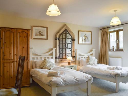 a bedroom with two beds and a chair in it at Swallow Barn in Banbury