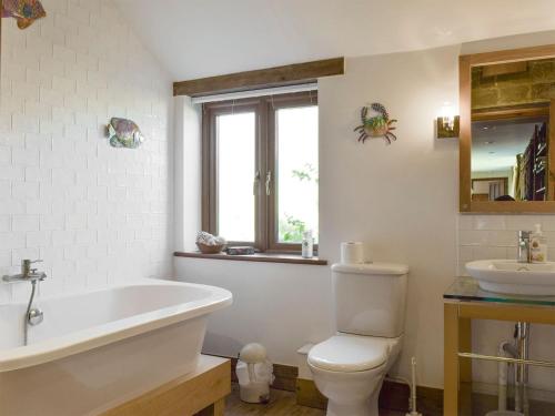 a bathroom with a tub and a toilet and a sink at Swallow Barn in Banbury