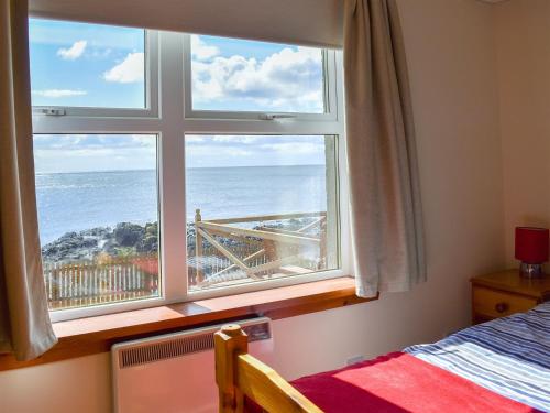 a bedroom with a window with a view of the ocean at Seashore Retreat in Johnshaven