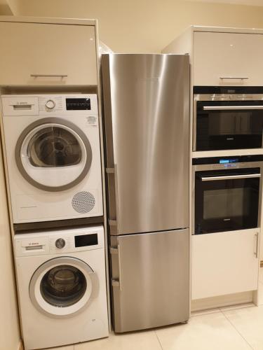 a kitchen with a refrigerator and a washer and dryer at London Luxury 1 bed flat 4 mins to Ilford Stn - kitchen, garden, parking, WiFi in Ilford