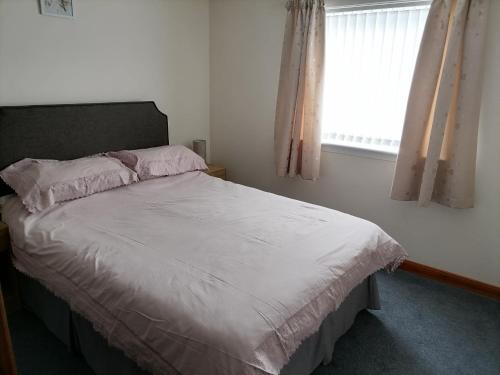 a bedroom with a white bed with a window at Impeccable 2-Bed Flat in Wick in Wick
