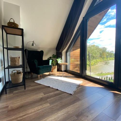 a living room with a green chair and a large window at Stodoła Nad Skawą in Sucha Beskidzka