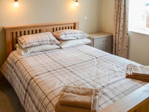 a bedroom with a large bed with pillows and a window at Grieves Cottage in Portmahomack