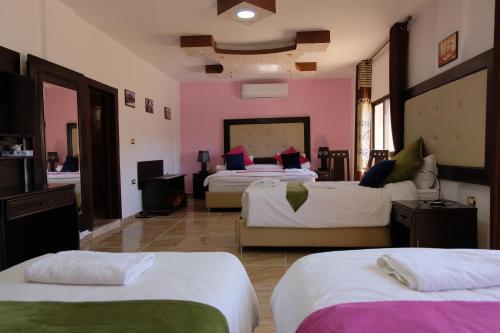 a room with three beds with pink walls at Petra Guests Hotel in Wadi Musa