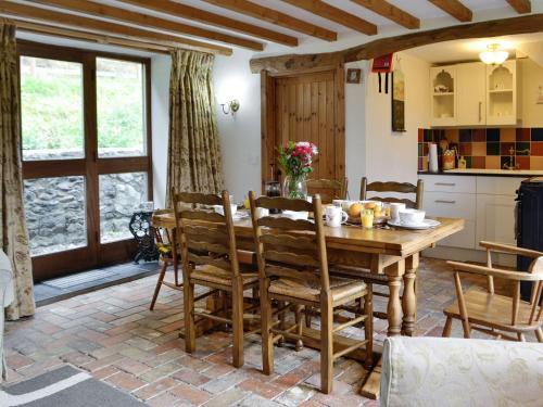 cocina y comedor con mesa de madera y sillas en The Hen House, en Llanfair-ar-y-bryn