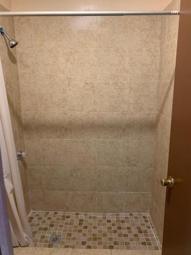 ducha con suelo de baldosa y cabina de ducha en Loma Alta Motel, en Laredo