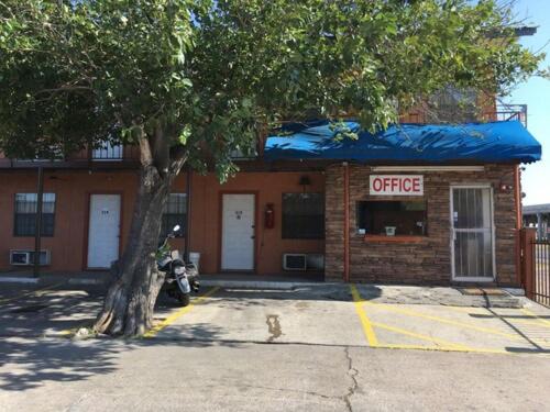 a coffee shop with a tree in front of it at Loma Alta Motel in Laredo