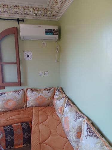 a bed with pillows in a room with a heater at Dar rachid ouzoud in Azilal