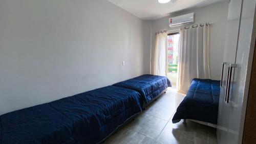 a bedroom with a blue bed and a window at Cobertura de 3 quartos com churrasqueira e piscina in Guarujá