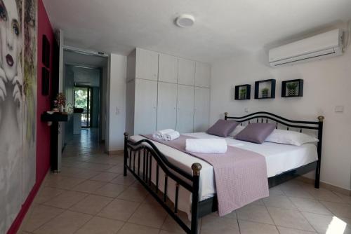 1 dormitorio con 1 cama grande con sábanas blancas y almohadas moradas en Ellie's StoneHouse Gianapa, Porto Rafti, Greece, 190 03, GR, en Porto Rafti