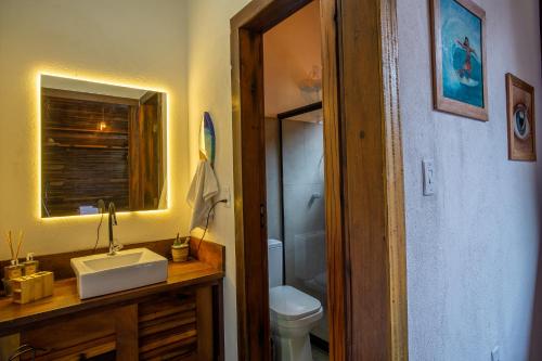 ein Badezimmer mit einem Waschbecken, einem WC und einem Spiegel in der Unterkunft Cabana Fluir - Taipu de Fora - Península de Maraú in Barra Grande