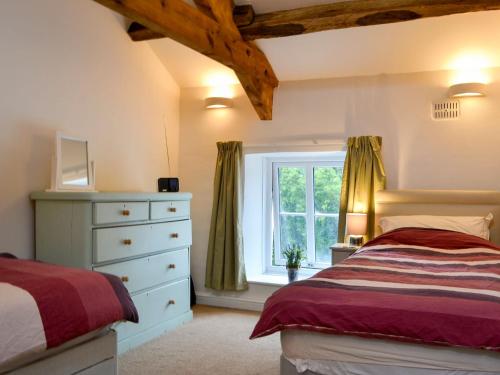 a bedroom with a bed and a dresser and a window at Taylors Cottage in Threlkeld