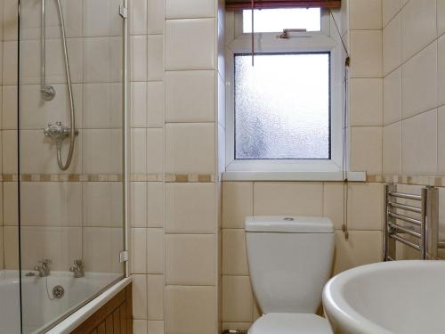 łazienka z toaletą, umywalką i oknem w obiekcie Three Rivers Cottage w mieście Pont-Nedd-Fechan