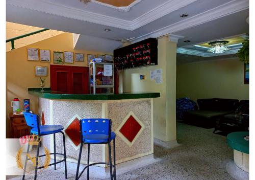 Hotel Nueva Esperanza في بارانكويلا: بار مع كراسي زرقاء وكاونتر مع زجاجات النبيذ