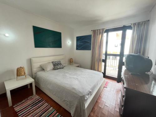 um quarto com uma cama, uma televisão e uma varanda em A Casa de Sesimbra com VISTA MAR by Trip2Portugal em Sesimbra