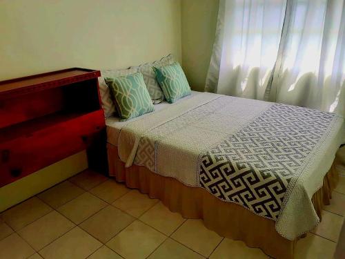 a bedroom with a bed with pillows and a window at Juju's Cottage with magnificent views in Laborie