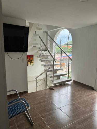 a living room with a staircase and a tv at Hostal Taganga Plaza in Taganga